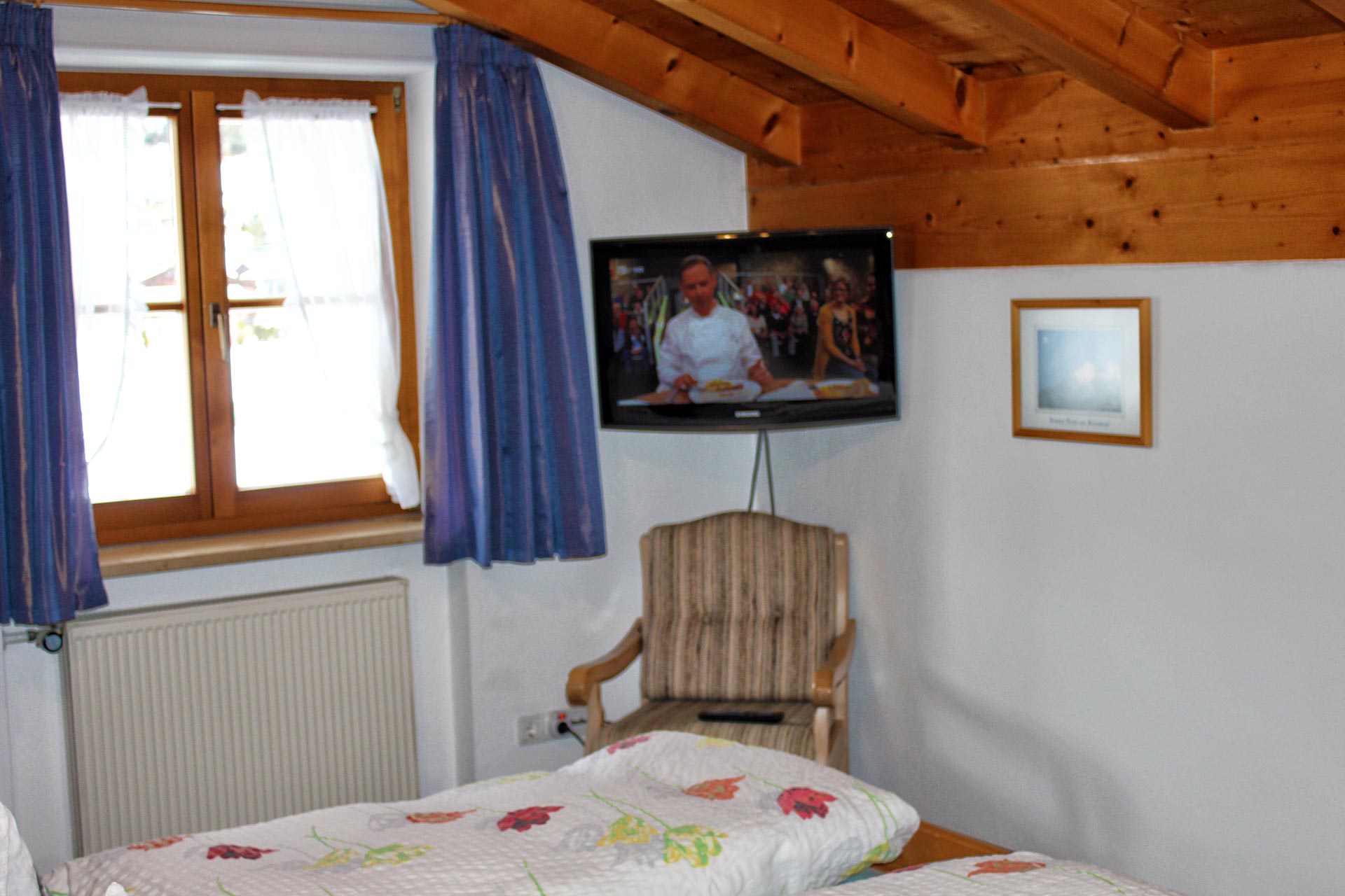 Blick auf Fernseher vom Bett im Schlafzimmer.